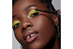 Image A girl putting on mascara with a bright green eyeshadow.